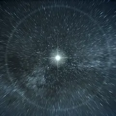 En ljuspunkt i mörkret, omgiven av strimmor av ljus som tycks röra sig snabbt. En visuell representation av ljusets hastighet i vatten.