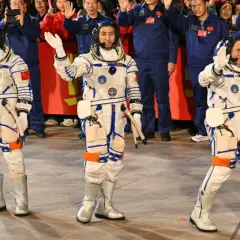 Astronaut Kina vinkar glatt till publiken i sin rymddräkt.