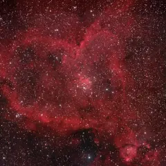 Ett kosmiskt hjärta av rött gasmoln och stjärnor, en hjärtnebulosa som lyser i rymden.