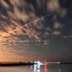 Långa ljusstrimmor på natthimlen, som visar satelliter runt jorden, med moln som drar förbi och stjärnor som glimmar.