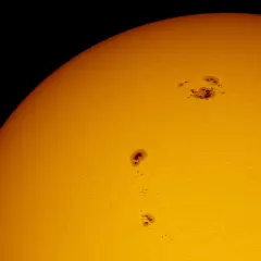 Solfläckar syns på solens yta, mörka områden som vittnar om solens ålder och aktivitet.