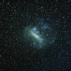 En stjärnklar natthimmel med det stora magellanska molnet som en lysande, oregelbunden form i mitten, omgivet av otaliga stjärnor.