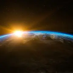 Jordens krökning med en glödande soluppgång över molnen. En påminnelse om liv i rymden och vår plats i universum.