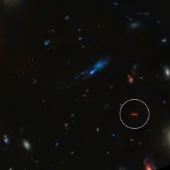 En avlägsen galax, likt en glödande orion nebulosan, lyser i mörkret bland andra kosmiska objekt.