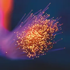 Ljus som strömmar genom fiberoptik, där varje ljuspunkt kan liknas vid en foton. Frågan om har fotoner massa är fascinerande.