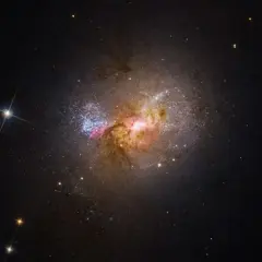 En galax med lysande gasmoln och stjärnor, liknande de magellanska molnen, lyser upp den mörka rymden.
