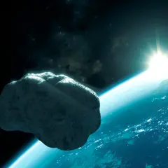 En stor asteroid svävar nära jorden. Solen går upp över planeten, som lyser med stadsljus.