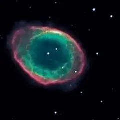 Den kosmiska ringnebulosan lyser i grönt och rosa mot en mörk stjärnhimmel.