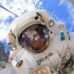 Astronaut med svensk flagga på dräkten, vinkar från rymden. Här arbetade Fuglesang på.