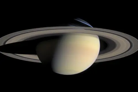 Saturnus med sina ringar, där nattsidan visar den kalla saturnus temperatur.