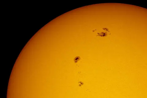 Solfläckar syns på solens yta, mörka områden som vittnar om solens ålder och aktivitet.