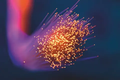 Ljus som strömmar genom fiberoptik, där varje ljuspunkt kan liknas vid en foton. Frågan om har fotoner massa är fascinerande.