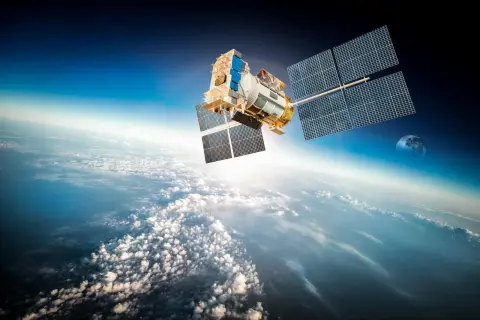 En satellit svävar över molnen. Hur många satelliter finns det egentligen i rymden? Månen syns i bakgrunden.