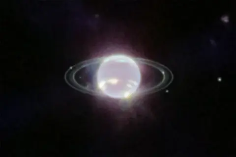 Neptunus ringar lyser i mörkret.