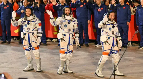 Astronaut Kina vinkar glatt till publiken i sin rymddräkt.
