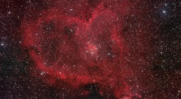 Ett kosmiskt hjärta av rött gasmoln och stjärnor, en hjärtnebulosa som lyser i rymden.
