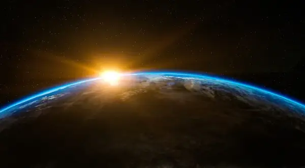 Jordens krökning med en glödande soluppgång över molnen. En påminnelse om liv i rymden och vår plats i universum.