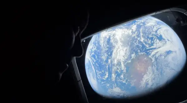 Silhuett av en person som tittar ut genom ett fönster på jorden från rymden. ISS Sverige.