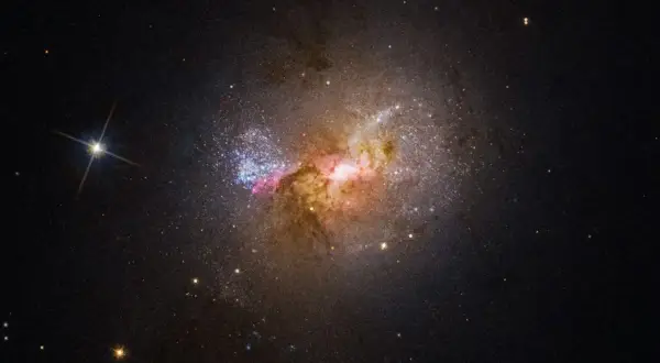 En galax med lysande gasmoln och stjärnor, liknande de magellanska molnen, lyser upp den mörka rymden.