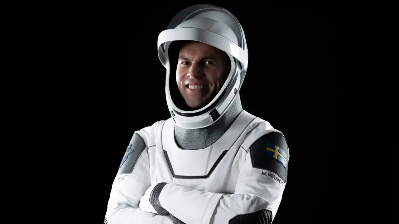 Marcus Wandt, en svensk astronaut, ler i sin rymddräkt med Sveriges flagga på axeln.