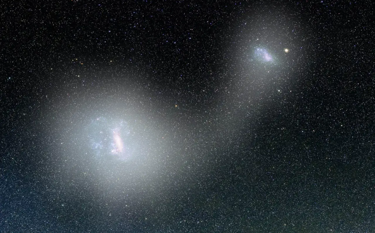 Tv&aring; lysande magellanska molnen lyser upp den stj&auml;rnbestr&ouml;dda natthimlen, som kosmiska juveler i m&ouml;rkret.