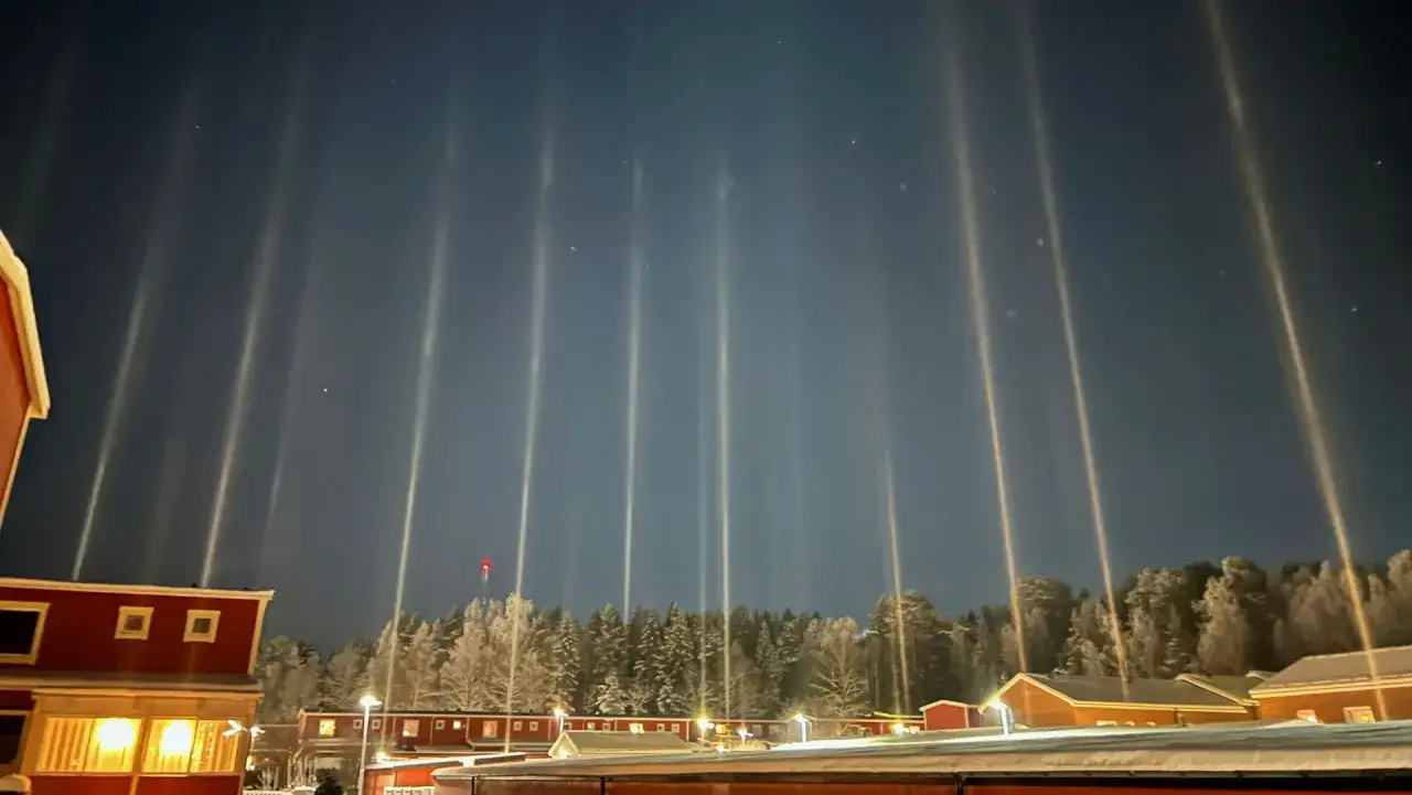 Vackra ljuspelare str&auml;cker sig mot natthimlen &ouml;ver sn&ouml;t&auml;ckta tr&auml;d och r&ouml;da hus i Sverige.