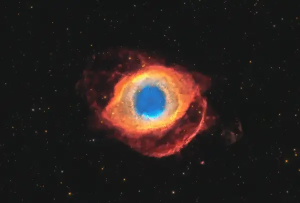 Helixnebulosan, ett kosmiskt öga av gas och stoft, lyser i rött och blått mot en stjärnbeströdd rymd.