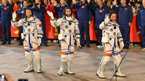 Astronaut Kina vinkar glatt till publiken i sin rymddräkt.