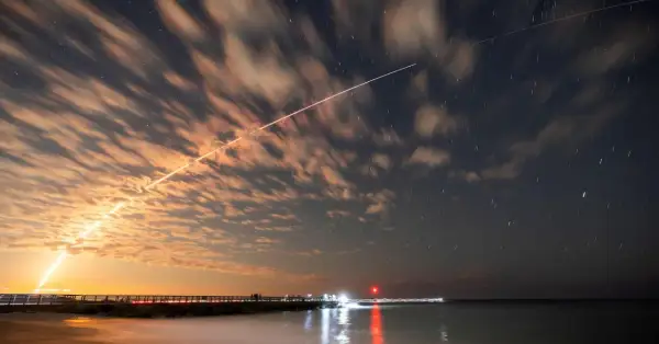 Långa ljusstrimmor på natthimlen, som visar satelliter runt jorden, med moln som drar förbi och stjärnor som glimmar.